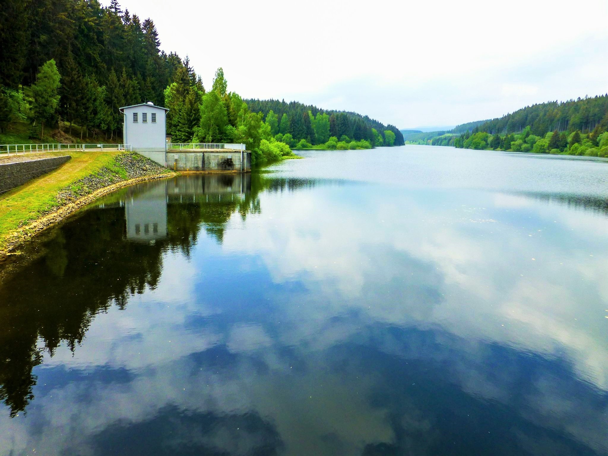 Stausee mit Wald und kleinem Gebäude am Ufer