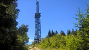Radio mast in the forest under a blue sky