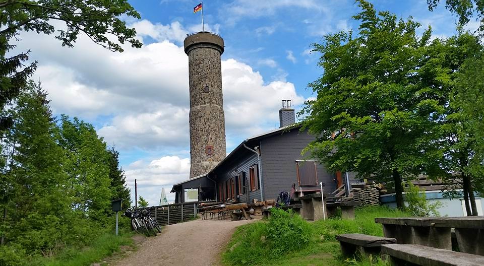 Steinerner Aussichtsturm neben Wanderhütte im Grünen