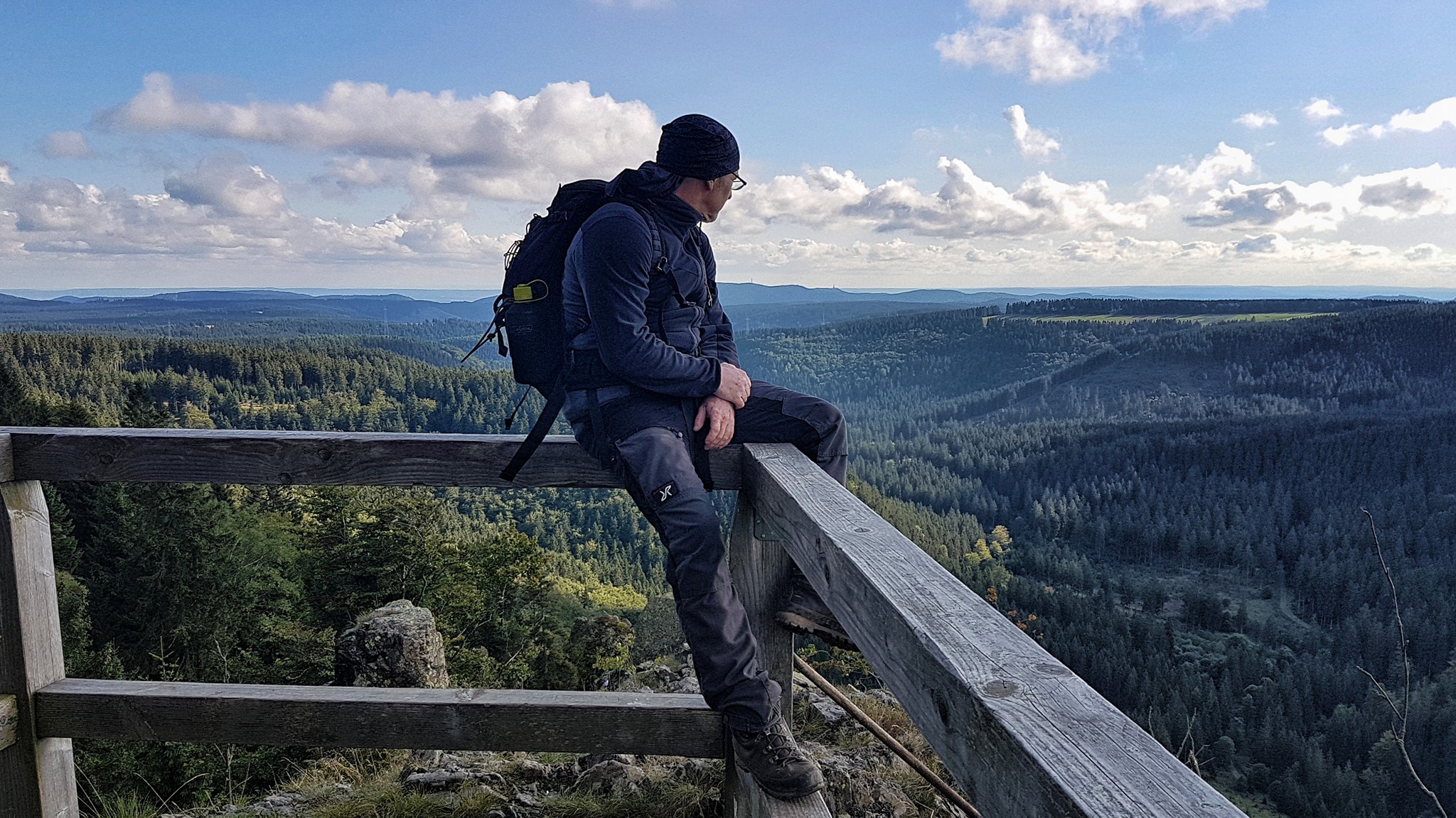 Hiker enjoys the view over wooded mountains