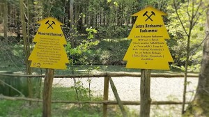 Yellow signs in the forest provide information about the water wheel and wheel chamber