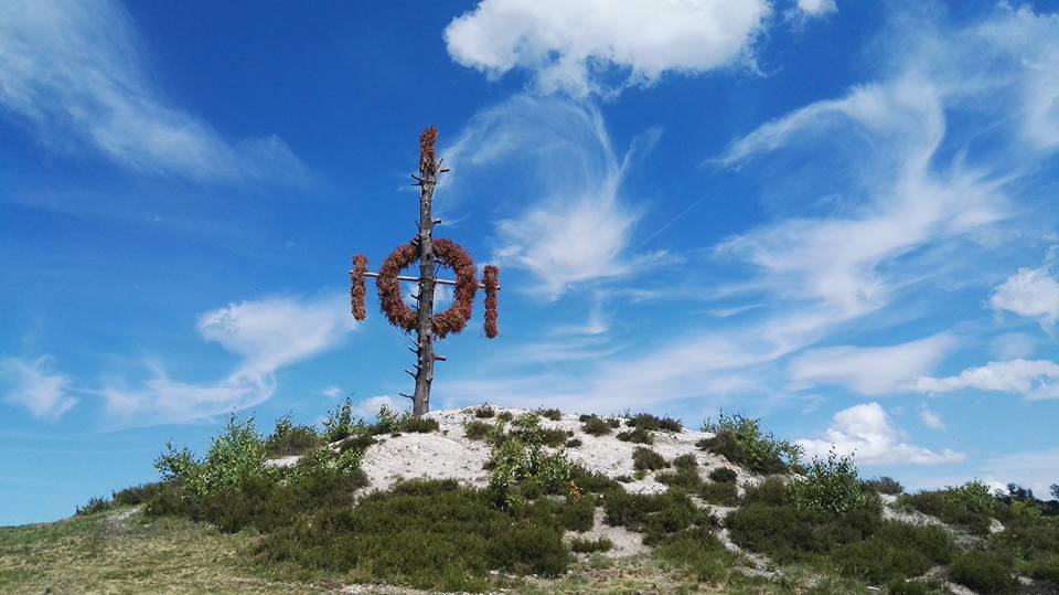 Holzskulptur auf Hügel unter blauem Himmel