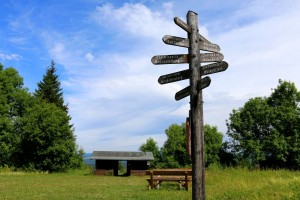 Signpost on meadow with trees and hut