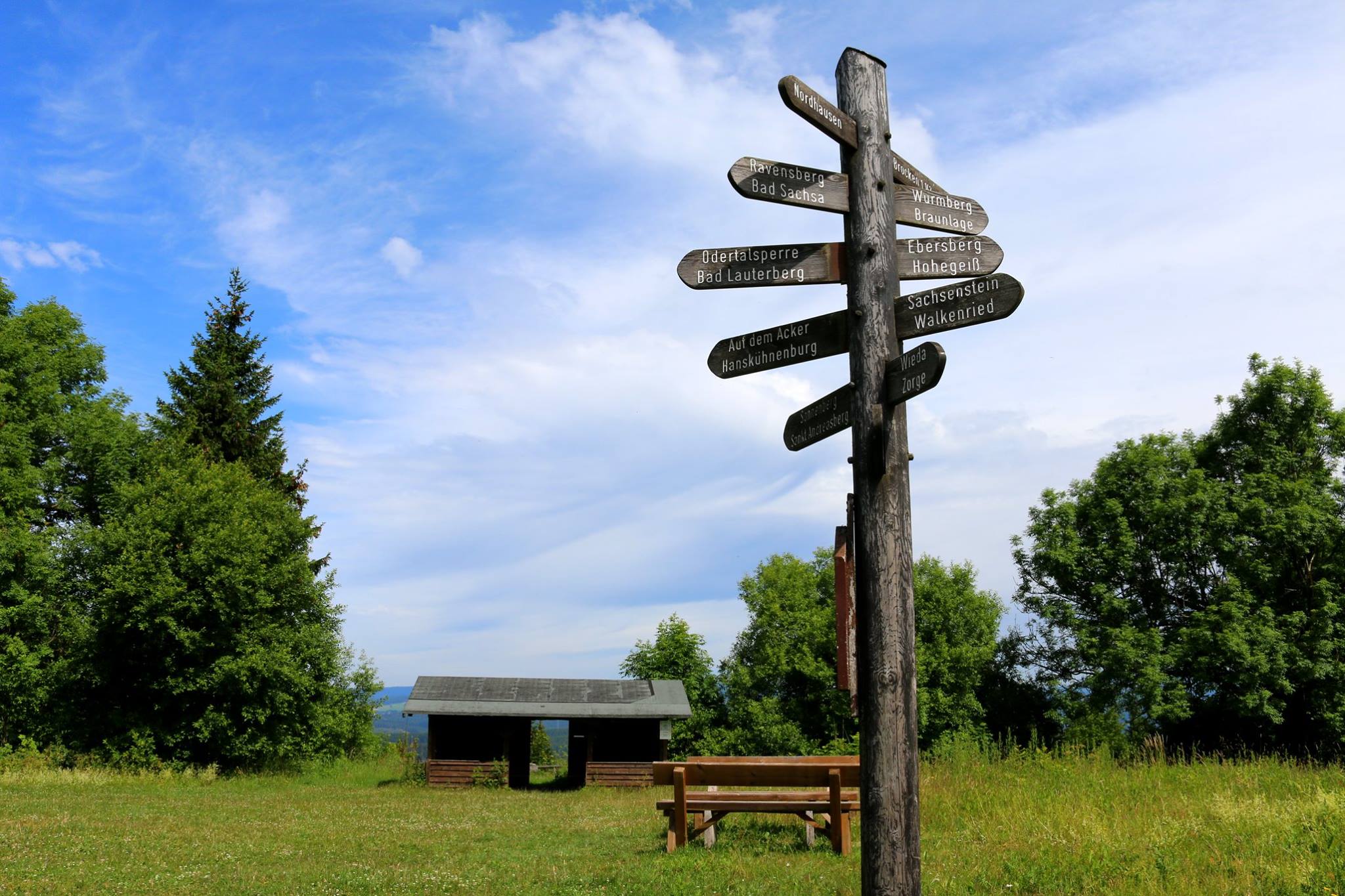 Signpost on meadow with trees and hut