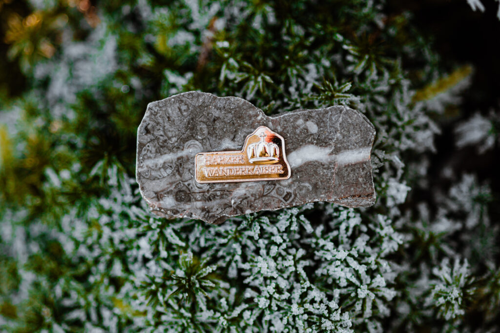 Harzer Wanderkaiser badge on stone in the snow