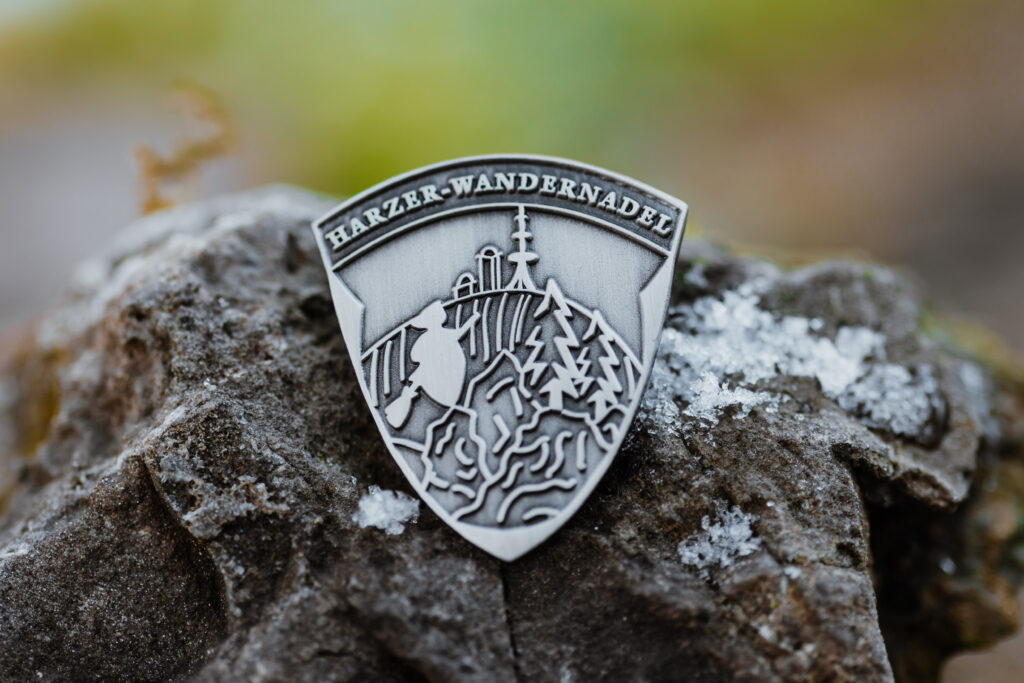 Harzer Wandernadel badge in silver on rocks.on rocks